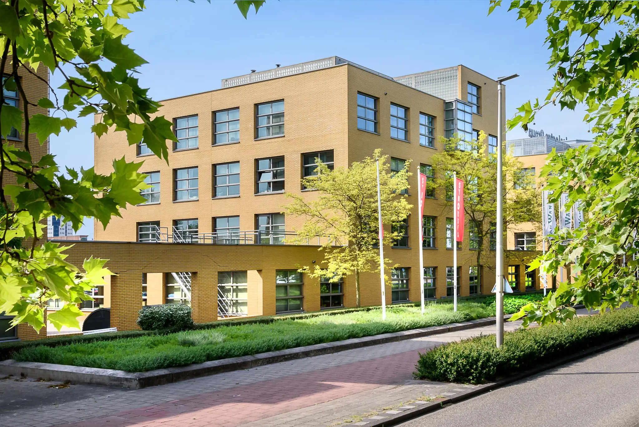 Modern kantoorgebouw aan de Rivium 2e Straat in Capelle aan den IJssel, omgeven door groen en vlaggen.